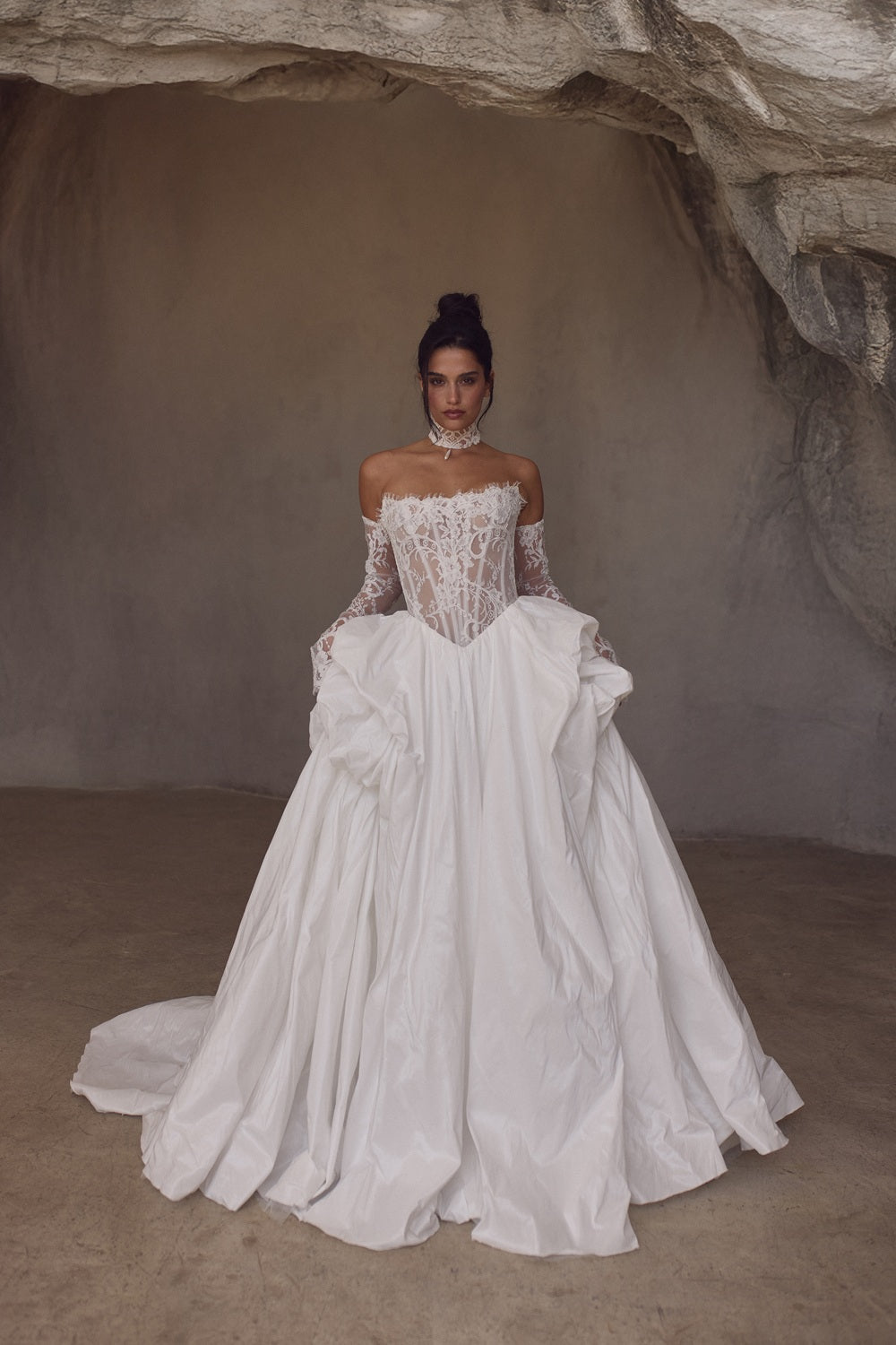 Woman in a white wedding dress standing in a cave-like setting